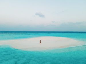 Far away shot of single person standing on a secluded sandbar, Maldives