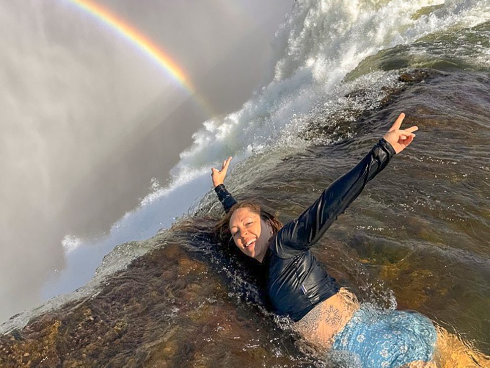 Woman over Victoria Falls with rainbow