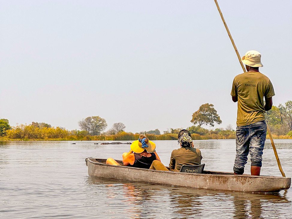3 people on small boat on the river Botswana