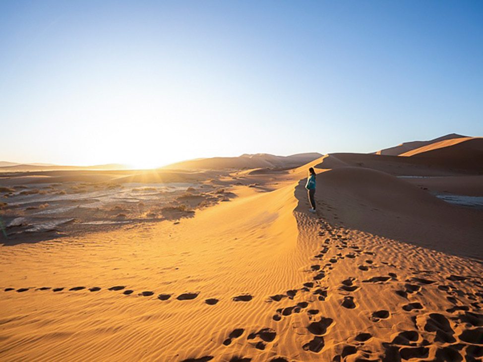 Woman and her footsteps in sand dune Namibia