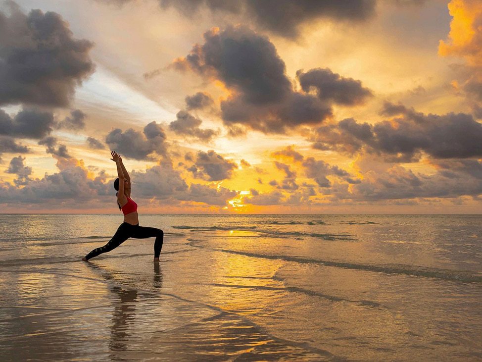 Women doing yoga pose ocean Maldives