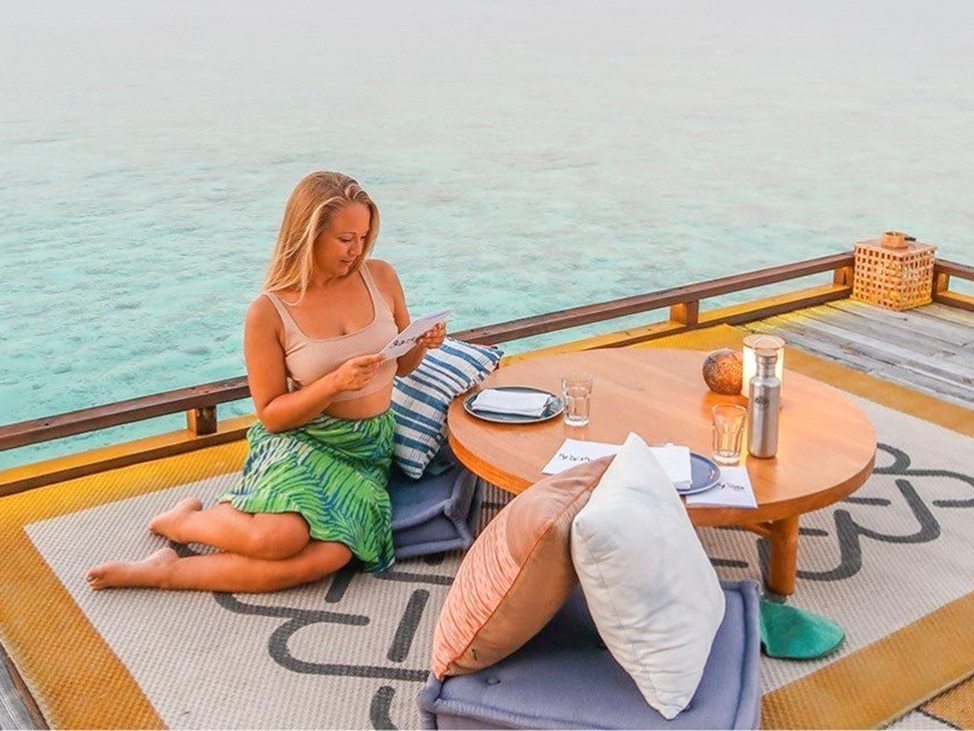Woman reading on deck by the ocean in the Maldives